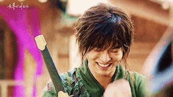 a young man is holding a sword and smiling .