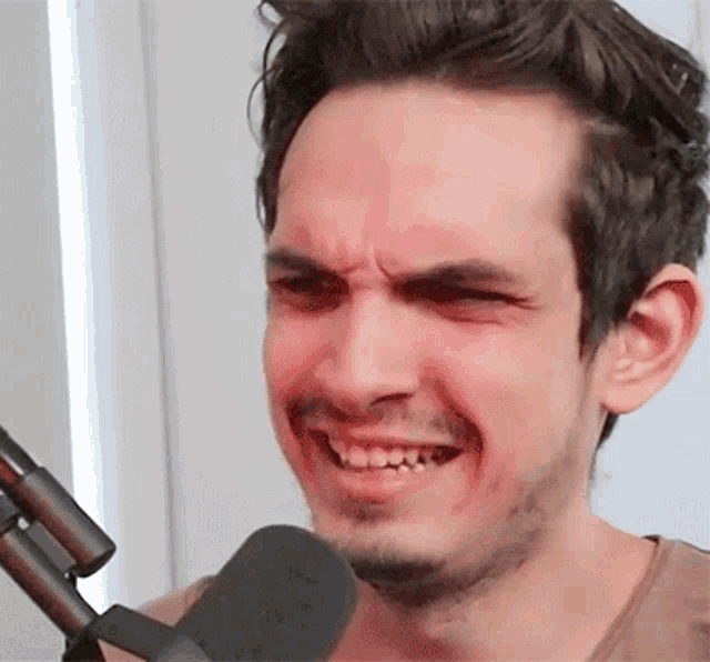 a man with a beard is making a funny face while holding a microphone .