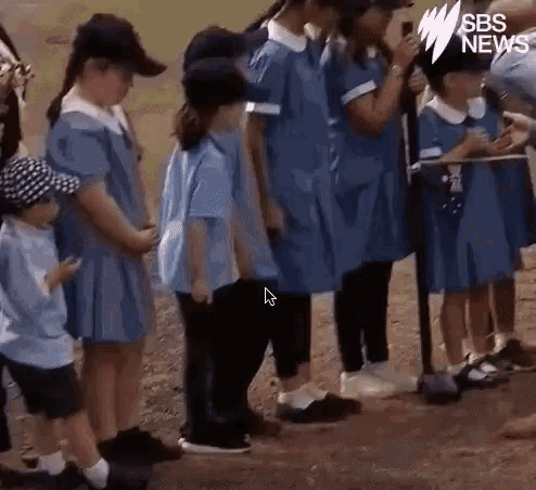a group of children are standing next to each other in a line .