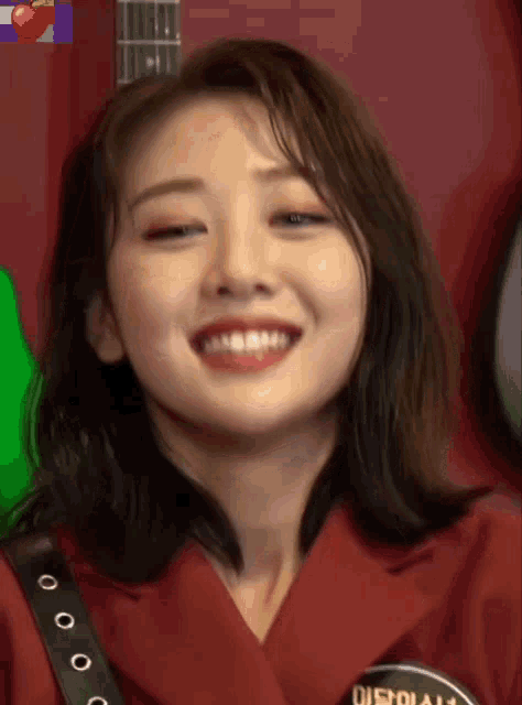 a close up of a woman 's face smiling in front of a guitar .