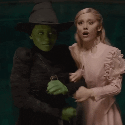 a woman in a white dress is standing next to a witch