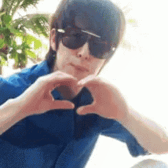 a man wearing sunglasses making a heart shape with his hands
