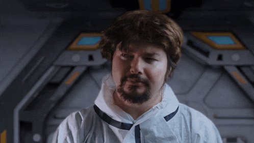 a man with a beard is wearing a white coat and tie