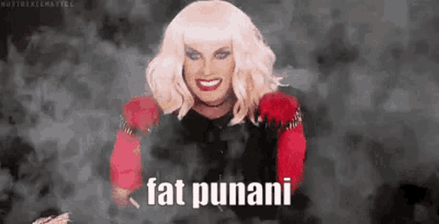 a drag queen is smiling in front of a smokey background while wearing a wig .