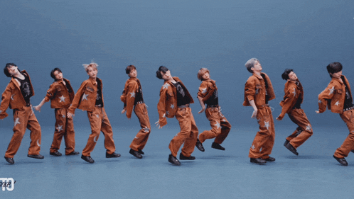 a group of young men are dancing in front of a blue background with the number 73 in the corner