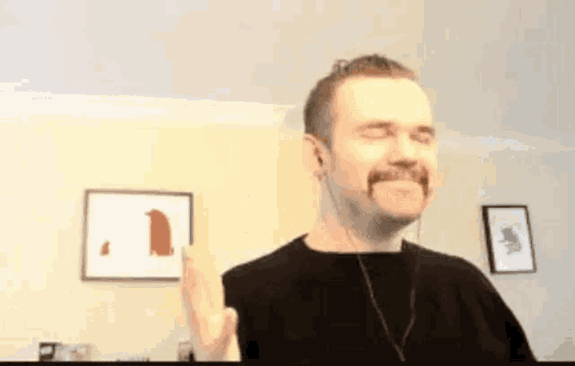 a man with a mustache wearing headphones is making a funny face .