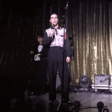 a man singing into a microphone on stage
