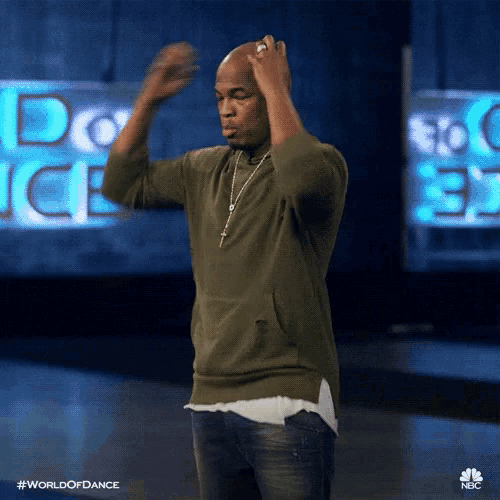 a man in a green sweater and jeans is dancing in front of a sign that says world of dance