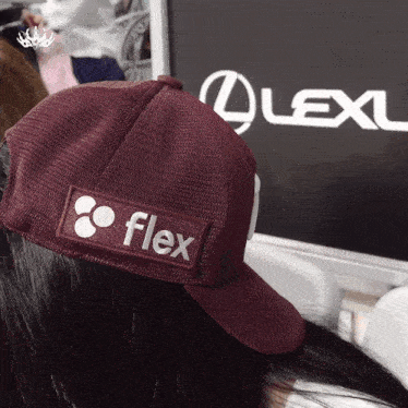 a person wearing a flex hat stands in front of a lexus sign