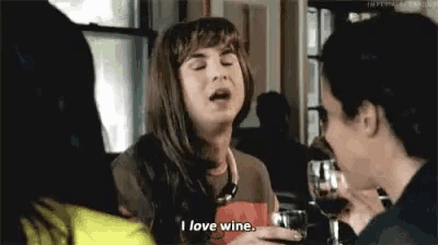 a woman is sitting at a table with a glass of wine .
