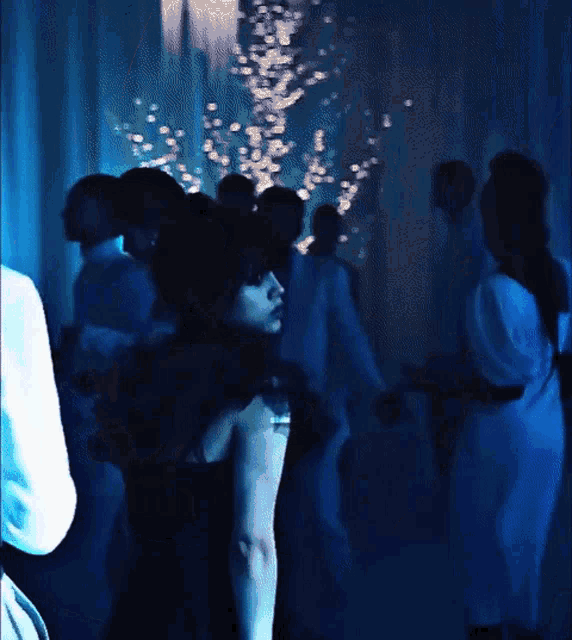 a woman in a black dress is standing in a crowded room