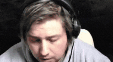 a man wearing headphones and a microphone is sitting in front of a computer screen .