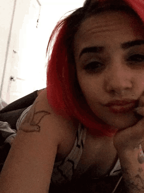 a woman with red hair and a tattoo of a bird on her arm