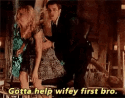 a man is holding a woman in his arms while another man says gotta help wifey first bro .