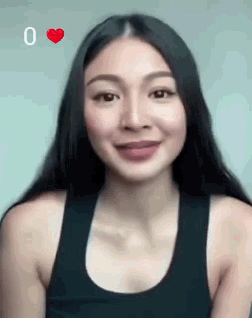 a woman in a black tank top is smiling with a red heart above her head