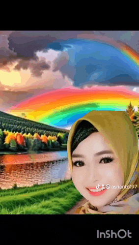 a woman in a hijab is smiling in front of a rainbow over a river .