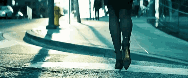 a woman in high heels crosses the street in front of a fire hydrant