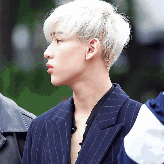 a young man with white hair is wearing a blue jacket