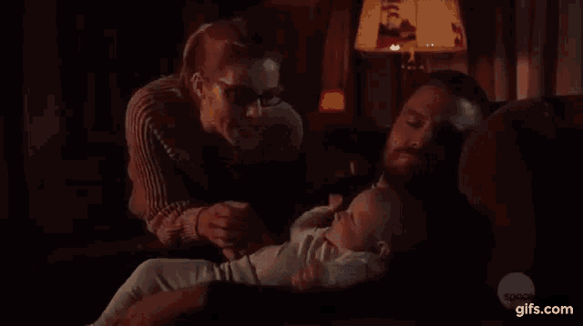 a man and a woman are sitting on a couch holding a baby in their arms .