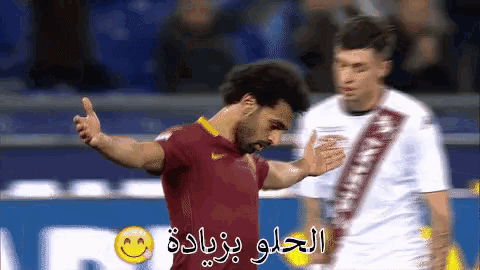 a soccer player in a red shirt is giving a thumbs up