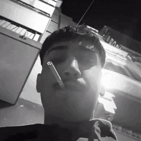 a man is smoking a cigarette in front of a building that says ' doo ' on it