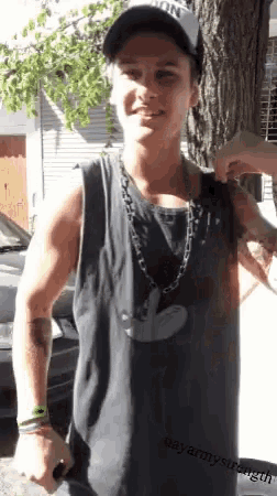a young man wearing a black tank top and a hat with the word army on it