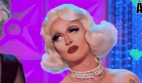 a drag queen with white hair and a pearl necklace is wearing a purple background .