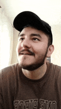 a man with a beard wearing a hat and a shirt that says ' tokyo evo ' on the front