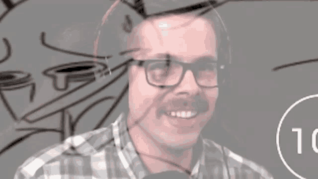 a man with glasses and a mustache is smiling in front of a drawing that says tc