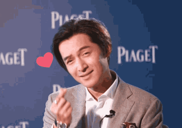 a man making a heart with his hand in front of piaget