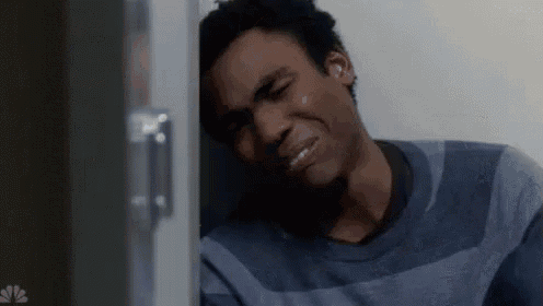 a man is leaning against a wall with his head on the wall and crying .