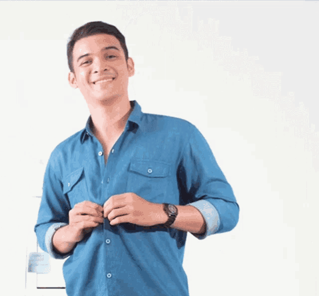 a man wearing a blue shirt and a watch is adjusting his shirt