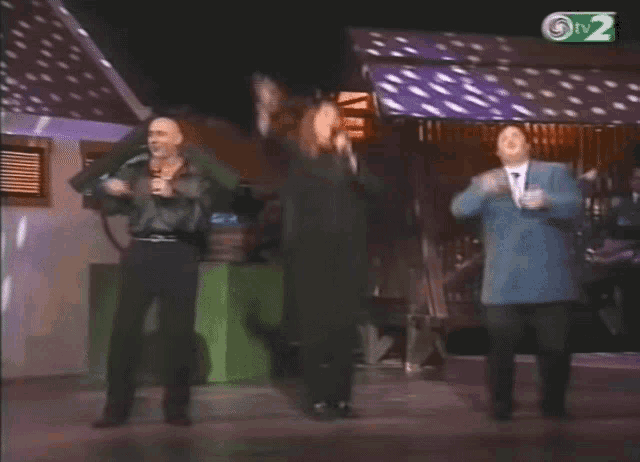 a group of people are dancing in front of a sign that says otv2