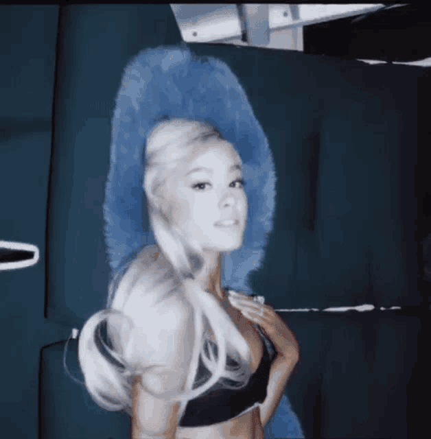 ariana grande is wearing a black bra and a blue furry hat .