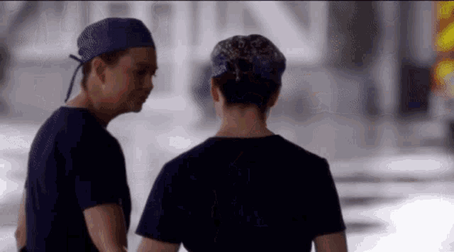 two female doctors wearing scrubs and purple hats are talking to each other