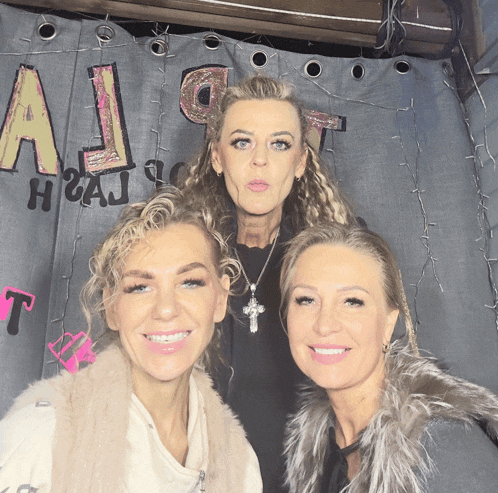three women are posing for a picture in front of a sign that says a1