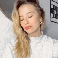the woman is wearing a white turtleneck sweater and earrings .