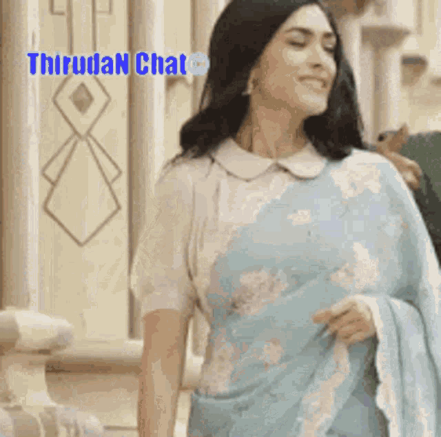 a woman wearing a light blue saree with a white collar is smiling