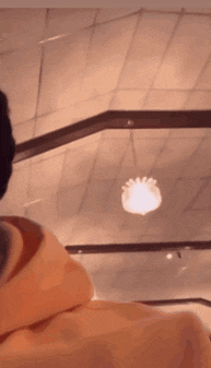 a person in a hoodie is looking up at a ceiling light