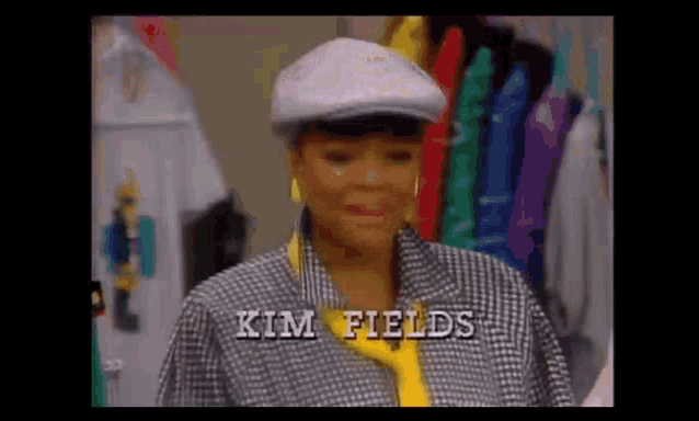 a woman wearing a hat and a jacket with the name kim fields written on the bottom