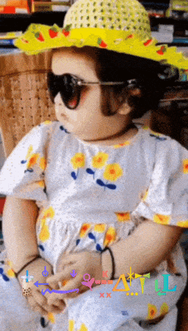 a little girl wearing a yellow hat and sunglasses with the letter l on the bottom