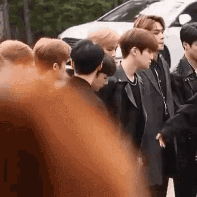 a group of young men are standing next to each other in front of a white car .