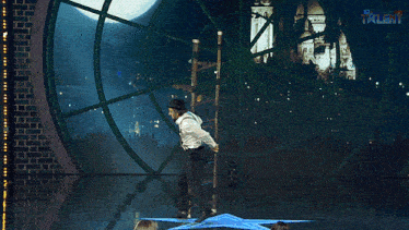 a man in a top hat and suspenders is balancing on a ladder in front of a ferris wheel that says talent