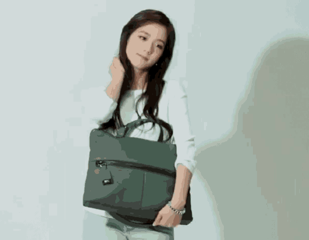 a woman in a white shirt is holding a gray purse