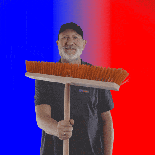 a man holding a broom with orange bristles