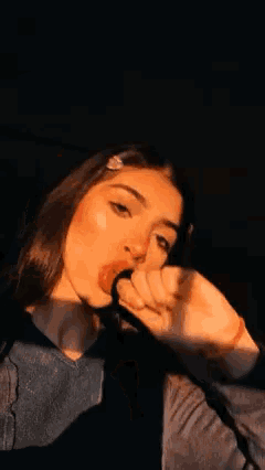 a girl is sticking her tongue out while holding a lollipop in her hand