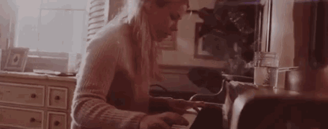 a woman in a sweater is cooking in a kitchen with a microwave in the background .