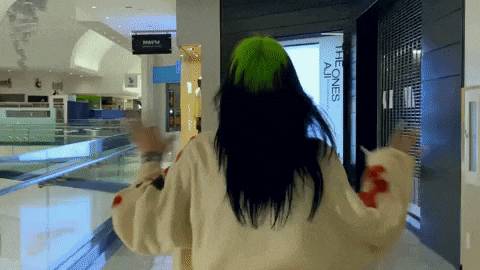 a woman in a green hat is walking through a mall with a sign that says the ones all