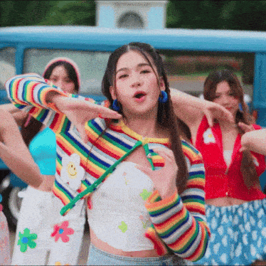 a woman wearing a rainbow sweater with a smiley face on the front