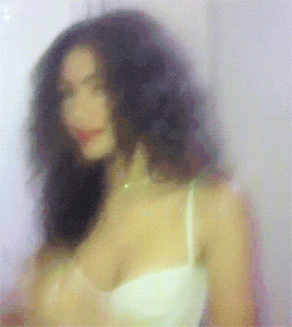 a blurry picture of a woman in a white bra and necklace